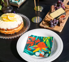 Allgifts Australia paper napkins featuring a vibrant Australian botanical print on a white plate at a table setting.